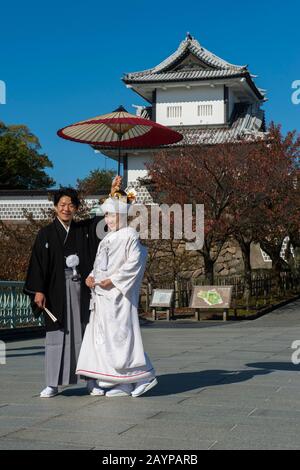 Ein Hochzeitspaar in traditioneller Kleidung posiert vor dem Schloss im Kaanazawa-Schlosspark in Canazawa, Präfektur Ishikawa, auf Honshu Isla Stockfoto
