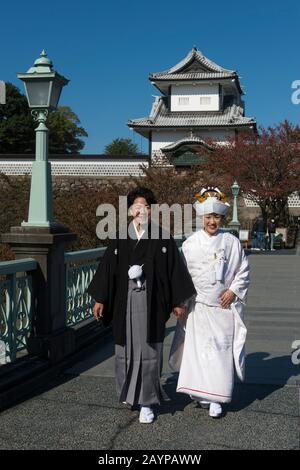 Ein Hochzeitspaar in traditioneller Kleidung posiert vor dem Schloss im Kaanazawa-Schlosspark in Canazawa, Präfektur Ishikawa, auf Honshu Isla Stockfoto