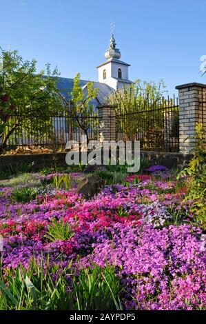 Landschaftsgestaltung rund um die Kirche mit schönen Blumen auf dem Hintergrund des blauen Himmels Stockfoto