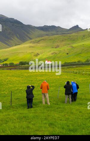 Menschen, die einen Bauernhof und eine Kirche in Asolfskali im Süden Islands fotografieren. Stockfoto