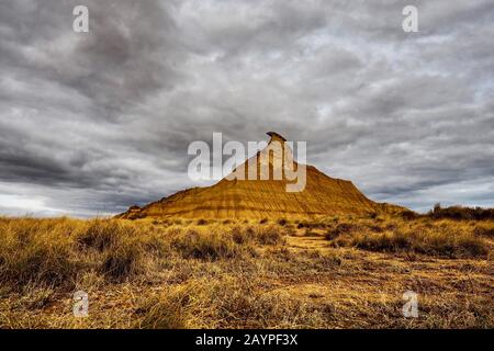 Extreme Wüstenlandschaft mit dramatischem Himmelshintergrund und berühmtem Peak Castil de Tierra in Bardenas Reales, Navarra, Spanien, Europa Stockfoto