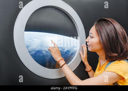 Frau, die den blauen Planeten durch den Strahler betrachtet Stockfoto