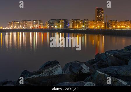 Die Skyline der Stadt Oostende (Ostende) mit Wasser und Pier in der Nacht mit ihren Lichtern im Nordseehafen, Belgien. Stockfoto