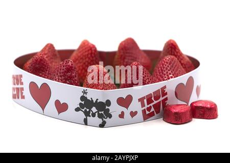 Herzförmige valentinsgeschenk mit Erdbeeren und eingepackter Schokoladenbonbons Stockfoto