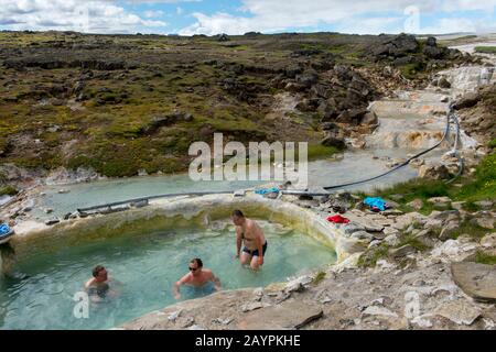 Die Menschen baden in einem Pool, der von heißen Quellen in Hveravellir gespeist wird, einem geothermischen Gebiet mit Fumarolen und mehrfarbigen heißen Pools im zentralen Hochland von Stockfoto