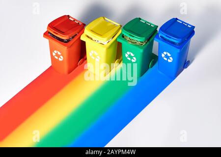 Vier farbcodierte Papierfächer, isometrische Projektion auf geometrischem Regenbogenpapierhintergrund mit Kopierraum. Recycling-Schild an den Behältern - rot, blau, yel Stockfoto