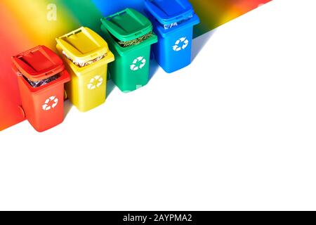 Vier farbcodierte Papierfächer, isometrische Projektion auf geometrischem Regenbogenpapierhintergrund mit Kopierraum. Recycling-Schild an den Behältern - rot, blau, Ye Stockfoto