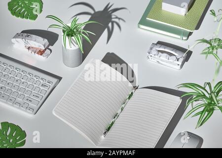 Konzepthintergrund mit modernen Büroartikeln in Weiß, Minzgrün und Marmor. Isometrische Projektion, geometrisches Layout mit Monstera-Blättern. Notizbuch, Stockfoto