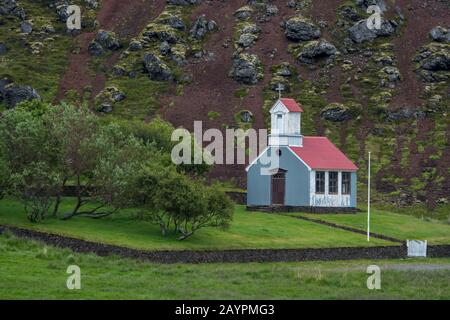 Ein Bauernhof und eine Kirche sitzen in einem Schlackenkrater Ytri Raudamelskula auf der Halbinsel Snaefellsnes im Westen Islands. Stockfoto