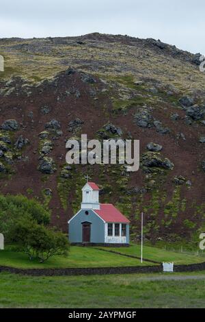 Ein Bauernhof und eine Kirche sitzen in einem Schlackenkrater Ytri Raudamelskula auf der Halbinsel Snaefellsnes im Westen Islands. Stockfoto