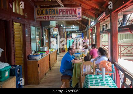 Menschen, die Meeresfrüchte in den kleinen Restaurants in der Markthalle in Angelmo, Puerto Montt im Süden Chiles essen. Stockfoto