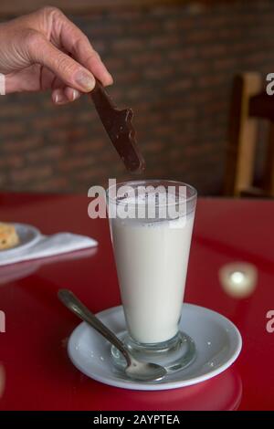Heiße Schokolade, die in einem Restaurant in der Nähe von Calafate, Argentinien, in heiße Milch getaucht wird. Stockfoto