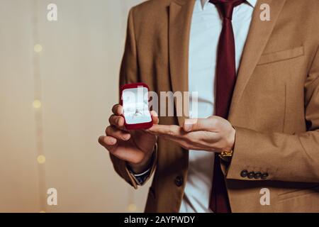 3/4-Blick auf den eleganten Mann, mit Box mit Hochzeitstring im Restaurant Stockfoto