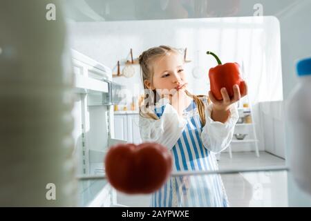 Selektive Fokussierung des pensiven Kindes auf Paprika Stockfoto