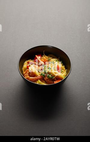 Nudeln mit Garnelen und Gemüse in Schüssel auf schwarzem Grund Stockfoto