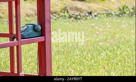 Das Alte Telefon steckte in das kleine Haus im Garten Stockfoto