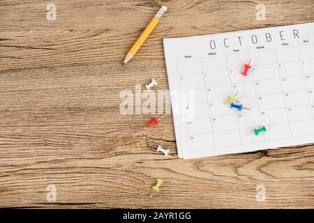 Draufsicht auf Bleistift, Bürostifte und Oktoberkalender auf Holzoberfläche Stockfoto