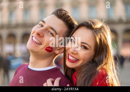 Junge lächelnde Paare Portrait, der Mann hat ein Lippenstiftkuss-Zeichen auf seiner Wange Stockfoto