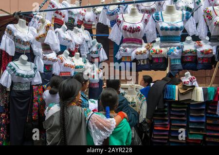 Einheimische Frauen kaufen Blusen auf dem lokalen Markt in der Stadt Otavalo im Hochland Ecuadors bei Quito ein. Stockfoto