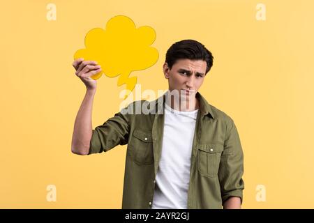 Verwirrter Mann, der eine Sprechblase in der Wolke hält, isoliert auf Gelb Stockfoto
