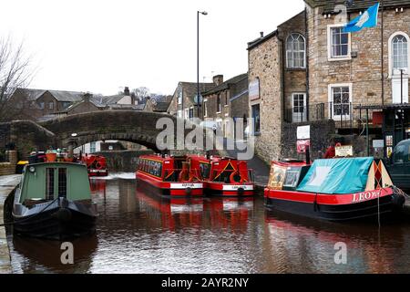 Farbenfrohe, Schmale Boote, die in Skipton auf dem Leeds to Liverpool Canal während der Wintermonate mit grauem Himmel über den meisten Booten auf dem Foto festgemacht wurden, können während der Touristensaison gemietet werden. Stockfoto