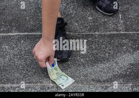 Bücken Sie sich nach unten und holen Sie sich ein Stück Singapur 5-Dollar-grüne Note auf dem Boden. Stockfoto