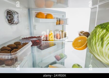 Frisches Obst, Häckchen und Kohlkohl im Kühlschrank mit offener Tür, isoliert auf weißem, Stockbild Stockfoto