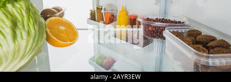 Frisches Obst, Häckselchen und Soßen im Kühlschrank mit offener Tür, isoliert auf weißem, Panoramabild, Stockbild Stockfoto