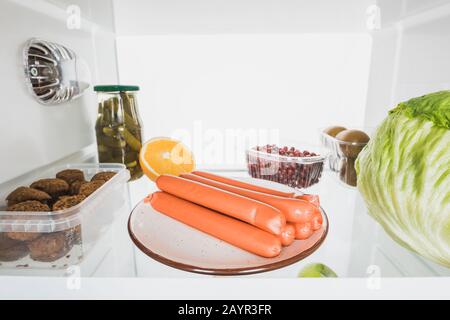 Würstchen, frisches Obst und Kohl auf dem Kühlschrankboden isoliert auf Weiß, Stockbild Stockfoto