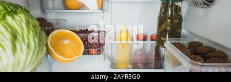 Panoramaaufnahme von frischen Früchten, Kohl mit Schnüppchen und Soßen im Kühlschrank, Stockbild Stockfoto