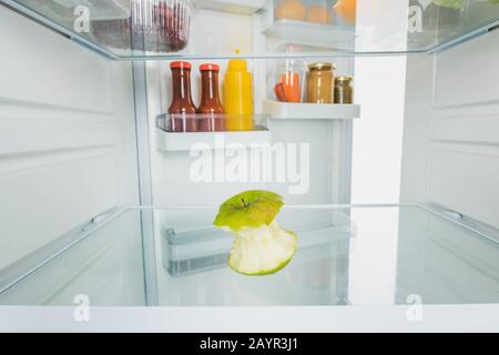 Selektive Fokussierung von gebittenem apfel mit Soßen auf offener Kühlschranktür, isoliert auf weißem, Stockbild Stockfoto
