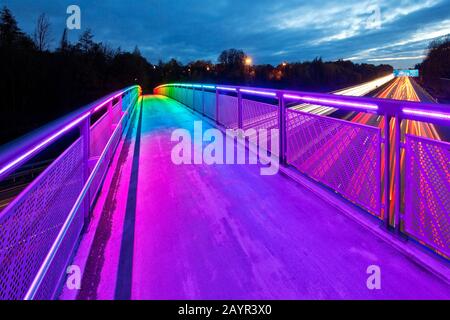 Beleuchtete Regenbogenbrücke über die Motoway A40 im Zwielicht, Deutschland, Nordrhein-Westfalen, Ruhrgebiet, Dortmund Stockfoto