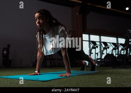 Afroamerikanische Frau steht in Plank auf Fitnessmatte Stockfoto