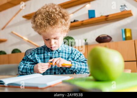 Selektive Fokussierung von niedlichen und intelligenten Kid, die Stift in der Nähe von grünem apfel halten Stockfoto