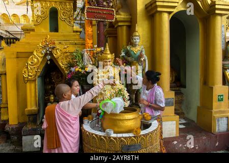 Menschen, die Wasser auf einen Buddha gießen und um Glück auf ihrem Planetenposten bei der 2.500 Jahre alten Shwedagon-Pagode in Yangon (Rangun), dem lar, bitten Stockfoto