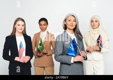 Multikulturelle Geschäftsfrauen mit Flaggen verschiedener Länder isoliert auf Weiß Stockfoto