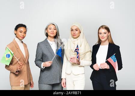 Multikulturelle Frauen mit Flaggen verschiedener Länder isoliert auf Weiß Stockfoto