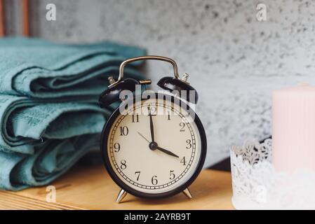 Massagezeit analoge schwarze Uhr auf einem Regal mit blauen Handtüchern und Wachskerzen. Das Konzept der Massageartikel. Stockfoto