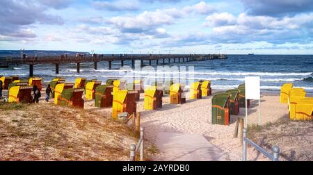 Sandstrände und traditionelle Holz-Strandstühle auf der Insel Rügen, Norddeutschland. Im Hintergrund die Seebrücke. Stockfoto