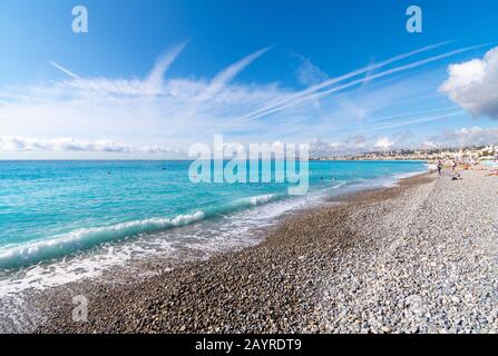 Eine kleine Welle bricht auf dem Kieselpfach entlang der französischen Riviera an der Angelbucht in Nizza, Frankreich. Stockfoto