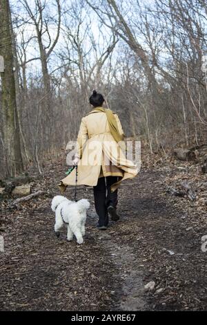 Frau läuft mit ihrer Kaninchenbegleiterin im Winter auf einem Weg in Prospect Park, Brooklyn, New York. Stockfoto