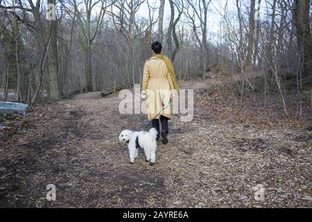 Frau läuft mit ihrer Kaninchenbegleiterin im Winter auf einem Weg in Prospect Park, Brooklyn, New York. Stockfoto