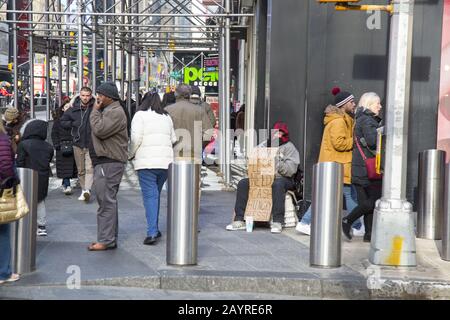 Obdachloser Mann bittet um Geld an der 7th Avenue in der immer überfüllten Times Square Nachbarschaft von Manhattan, New York City. Stockfoto