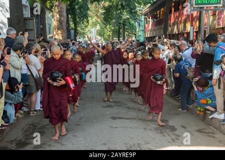 Buddhistische, von Hunderten von Touristen umgebene Mönch zerhaschen ihre Almosen (Mahlzeit) im Mahagandayon-Kloster in Mandalay, Myanmar. Stockfoto