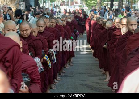 Buddhistische, von Hunderten von Touristen umgebene Mönch zerhaschen ihre Almosen (Mahlzeit) im Mahagandayon-Kloster in Mandalay, Myanmar. Stockfoto