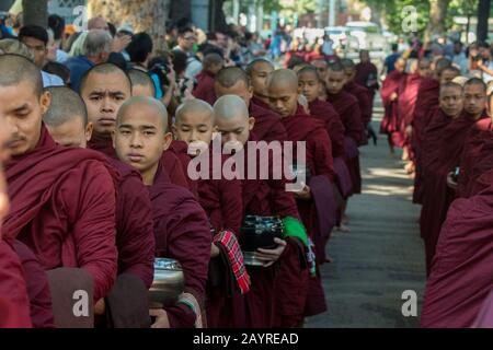 Buddhistische, von Hunderten von Touristen umgebene Mönch zerhaschen ihre Almosen (Mahlzeit) im Mahagandayon-Kloster in Mandalay, Myanmar. Stockfoto