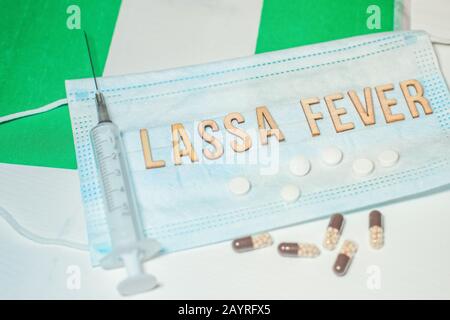 Nigerianische Flagge unter den Worten Lassa Fever Outbreak-Konzept. Atemschutzmaske und Spritze. Lassa hämorrhagisches Fieber LHF endemisch in Westafrika inkl Stockfoto