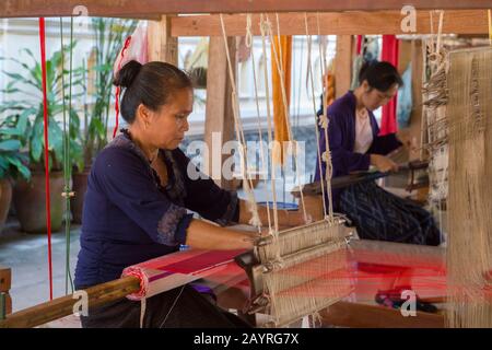 Frauen auf einem Webstuhl weben Seide- und Baumwollstoffe in einer Werkstatt in Ban Xang Khong, einem Dorf in der Nähe von Luang Prabang in Zentral-Laos, das für sie bekannt ist Stockfoto