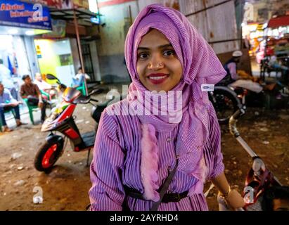 Eine muslimische Frau in lila, die sich an ihr Motorrad in Kolkata, Indien, lehnt Stockfoto