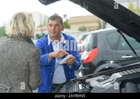 Mechaniker erklärt einer Frau den Motor Stockfoto